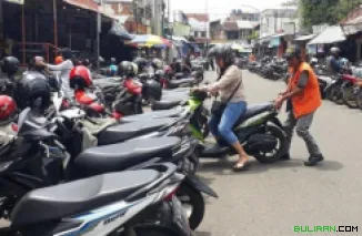 Tampilan seorang juru parkir yang sedang menata motor yang terparkir di atas trotoar di Kawasan Tanah Abang.